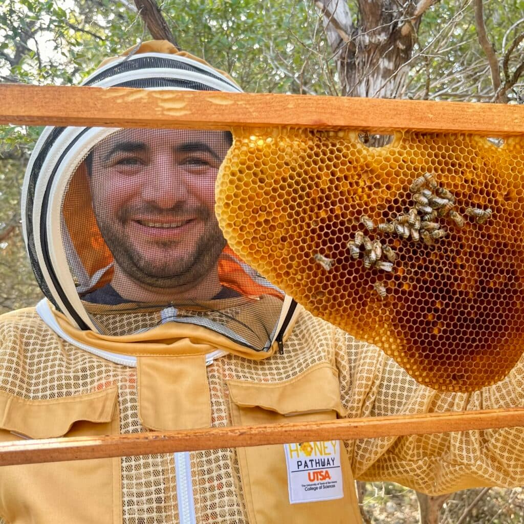 Prof. Dr. Ferhat Öztürk holding a honeycomb frame in the field